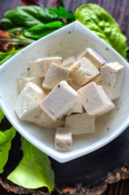 Taze vejetaryen ürünü, tofu. Baharat ve salata yapraklarıyla marine edilmiş bir tabakta soya grisi tofu.