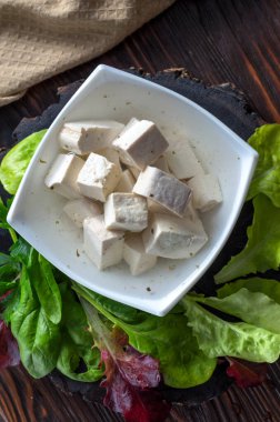 Taze vejetaryen ürünü, tofu. Baharat ve salata yapraklarıyla marine edilmiş bir tabakta soya grisi tofu.