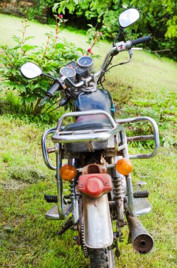 Motosiklet yaz bahçesinde, şehrin dışında, off-road yapmaya hazır bekliyor.