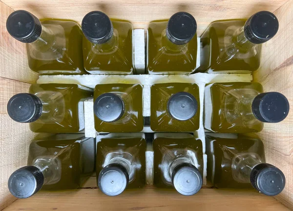 Olive oil bottles filled in wooden crate. Olive oil bottles prepared for shipping in glass bottles. Top view filled glass bottles. Selective focus.