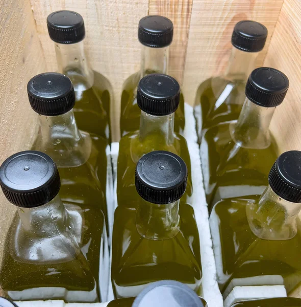 Glass olive oil bottles side by side in wooden crate. Olive oil in glass bottle. Selective focus.