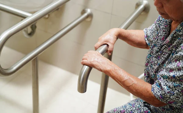 亚洲老年妇女患者在浴室使用厕所支撑架 扶手安全抓斗 护理医院安保 — 图库照片