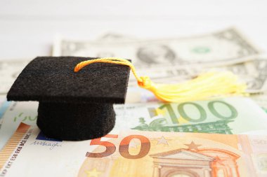 Avrupa ve ABD doları üzerindeki mezuniyet şapkası para, eğitim ücreti öğrenim öğrenimi öğretim konsepti.