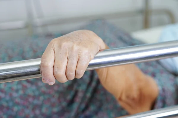 stock image Asian elder senior woman patient holding bed rail while lie down with hope waiting her family in hospital.