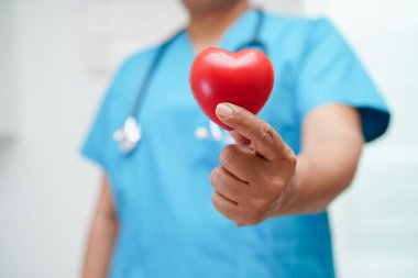 Asyalı kadın doktor hastanede sağlık için kırmızı kalp tutuyor..