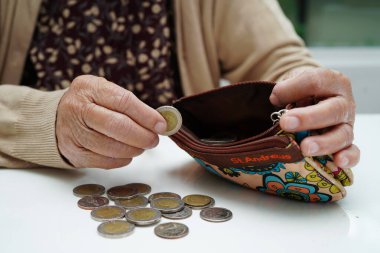 Retired elderly woman counting coins money and worry about monthly expenses and treatment fee payment.