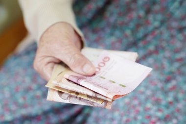 Retired elderly woman counting coins money and worry about monthly expenses and treatment fee payment.