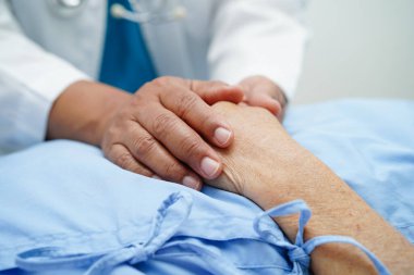 Doktor el ele tutuşuyor Asyalı yaşlı kadın hasta, hastanede yardım ve bakım.