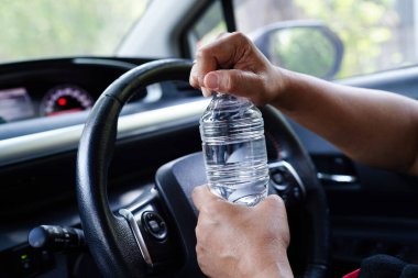 Asyalı kadın sürücü arabada soğuk su tutuyor, tehlikeli ve kaza riski var..
