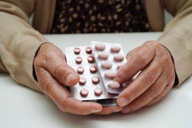 Asyalı yaşlı kadın elinde hap tutuyor, güçlü sağlıklı tıbbi konsept..