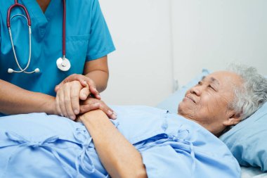 Doktor el ele tutuşuyor Asyalı yaşlı kadın hasta, hastanede yardım ve bakım.