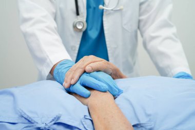 Doktor el ele tutuşuyor Asyalı yaşlı kadın hasta, hastanede yardım ve bakım.