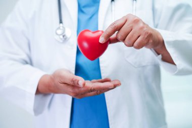 Asyalı kadın doktor hastanede sağlık için kırmızı kalp tutuyor..