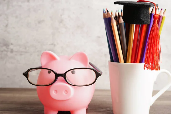 Pigging bank wearing eyeglass with coins and calculator saving bank education concept.