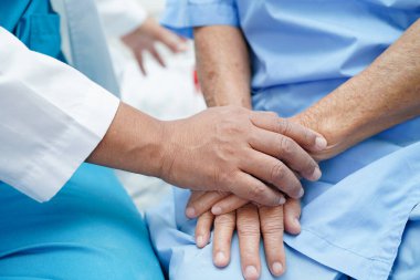 Doktor el ele tutuşuyor Asyalı yaşlı kadın hasta, hastanede yardım ve bakım.