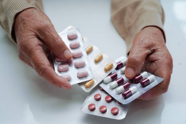 Asyalı yaşlı kadın elinde hap tutuyor, güçlü sağlıklı tıbbi konsept..