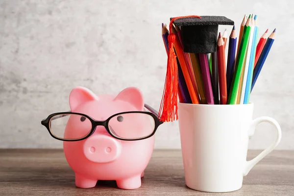 Pigging bank wearing eyeglass with coins and calculator saving bank education concept