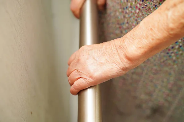 Asian elderly old woman patient use support rail on ramp, handrail safety grab bar, security in nursing hospital.