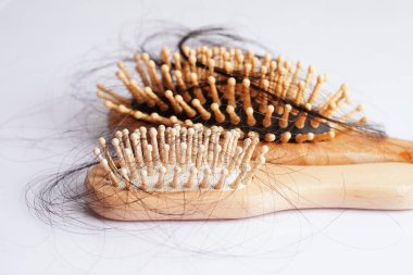 Tarak fırçasıyla beyaz arkaplanda saç kaybı.