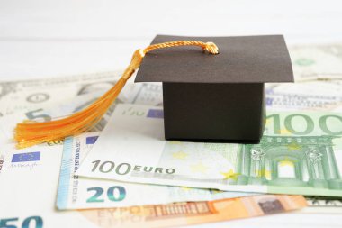 Avrupa ve ABD doları üzerindeki mezuniyet şapkası para, eğitim ücreti öğrenim öğrenimi öğretim konsepti.
