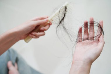 Asian woman have problem with long hair loss attach in her hand.
