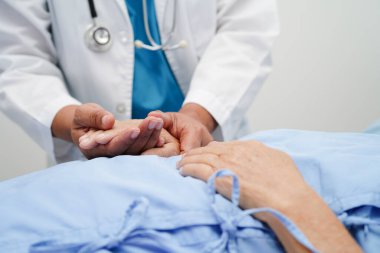 Doktor el ele tutuşuyor Asyalı yaşlı kadın hasta, hastanede yardım ve bakım.