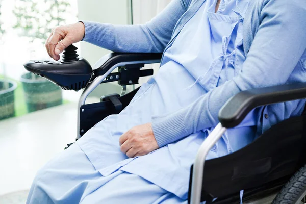Asian elderly woman disability patient sitting on electric wheelchair in park, medical concept.