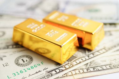 Gold bars on US dollar banknote money, finance trading investment business currency concept. 