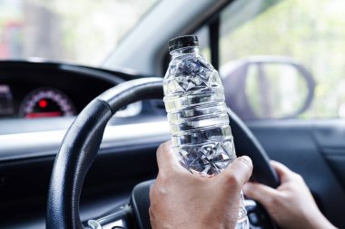 Asyalı kadın sürücü arabada soğuk su tutuyor, tehlikeli ve kaza riski var..