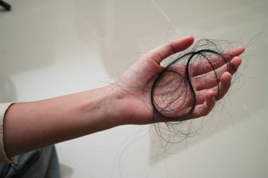Asian woman have problem with long hair loss attach in her hand.