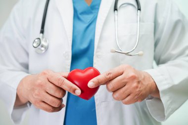 Asyalı kadın doktor hastanede sağlık için kırmızı kalp tutuyor..
