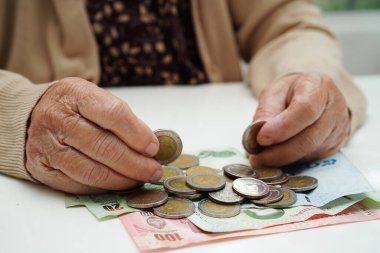 Retired elderly woman counting coins money and worry about monthly expenses and treatment fee payment.