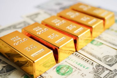 Gold bars on US dollar banknote money, finance trading investment business currency concept. 