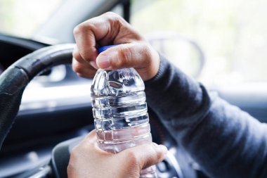 Asyalı kadın sürücü arabada soğuk su tutuyor, tehlikeli ve kaza riski var..