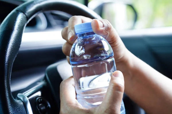 stock image Asian woman driver hold cold water for drink in car, dangerous and risk an accident.