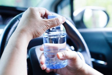 Asyalı kadın sürücü arabada soğuk su tutuyor, tehlikeli ve kaza riski var..