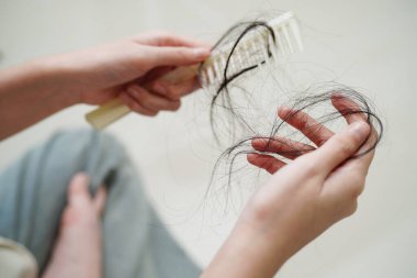 Asian woman have problem with long hair loss attach in her hand.