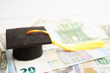 Avrupa ve ABD doları üzerindeki mezuniyet şapkası para, eğitim ücreti öğrenim öğrenimi öğretim konsepti.