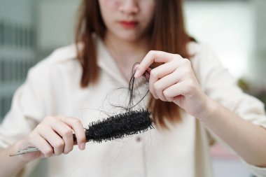 Asian woman have problem with long hair loss attach in her hand.    