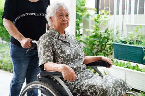 Caregiver help Asian elderly woman disability patient sitting on wheelchair in hospital, medical concept.