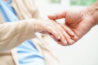 Doktor el ele tutuşuyor Asyalı yaşlı kadın hasta, hastanede yardım ve bakım.   