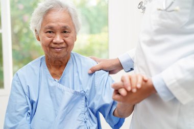 Doktor el ele tutuşuyor Asyalı yaşlı kadın hasta, hastanede yardım ve bakım.