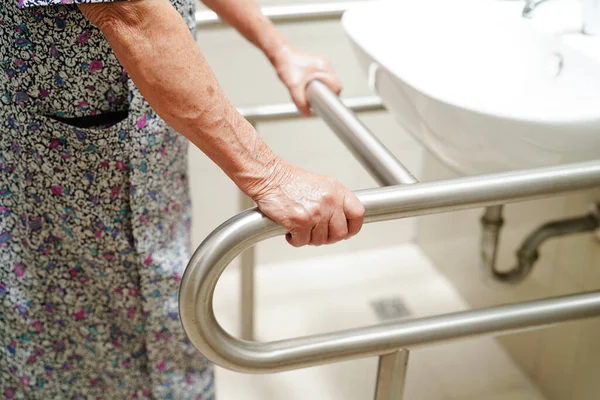 アジアの高齢女性患者は バスルーム 手すり安全グラブバー 看護病院のセキュリティでトイレサポートレールを使用しています — ストック写真
