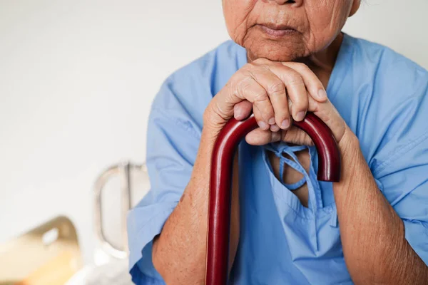 亚洲老年残疾妇女患者手握手杖 双手皱巴巴地躺在医院里 — 图库照片