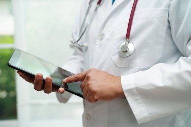 Hastanedeki hastaları arama yöntemi için cep telefonu ya da tablet tutan Asyalı kadın doktor.  