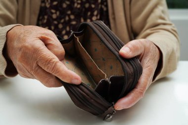 Retired elderly woman counting coins money and worry about monthly expenses and treatment fee payment.