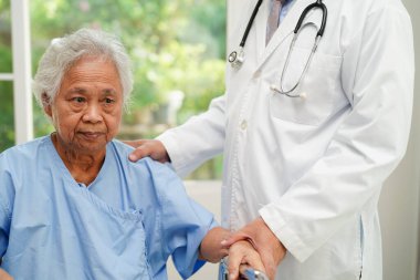Doktor, Asyalı yaşlı kadın engelli hastaya hemşirelik hastanesinde Walker 'la birlikte yürümesi için yardım ediyor..