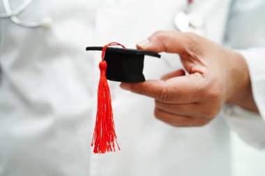 Hastanede elinde mezuniyet şapkası olan Asyalı kadın doktor. Tıp eğitimi konsepti..