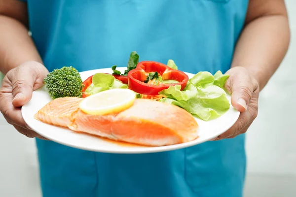 病院での健康食品のためのサーモンステークと野菜サラダを保持医師 — ストック写真
