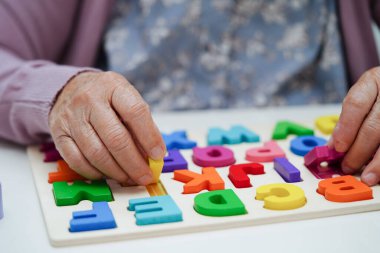 Yaşlı Asyalı kadın bunama ve Alzheimer hastalıklarını önlemek için beyin eğitimi oyunu oynuyor..